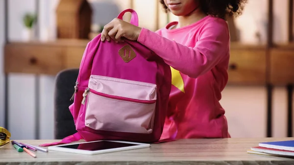 Partial view of african american child holding packed backpack — Stock Photo