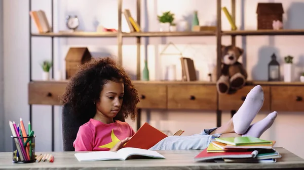 Afrikanisch-amerikanisches Kinderbuch mit Beinen auf dem Schreibtisch — Stockfoto