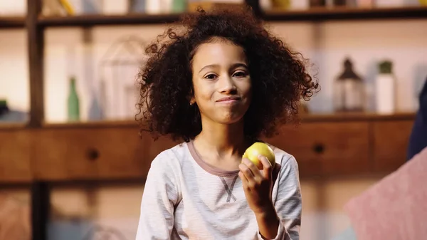 Niño afroamericano sonriendo mientras come manzana - foto de stock