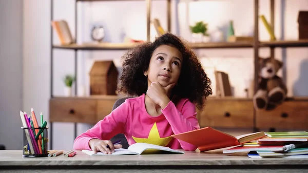 Thoughtful african american schoolkid doing homework — Stock Photo