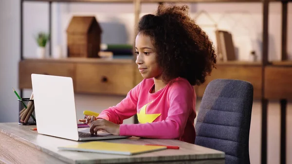 Sorrindo afro-americano estudante usando laptop ao fazer lição de casa — Fotografia de Stock