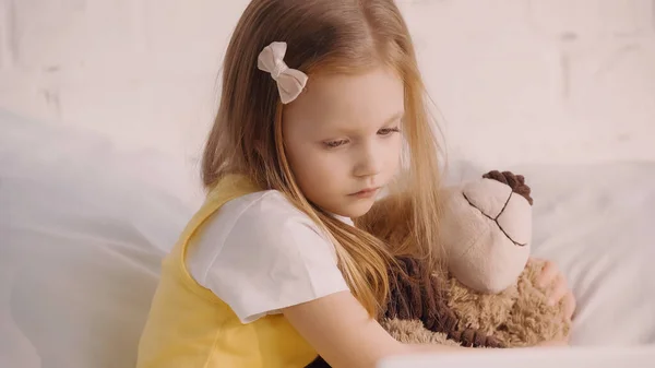 Kind umarmt Teddybär zu Hause im Bett — Stockfoto