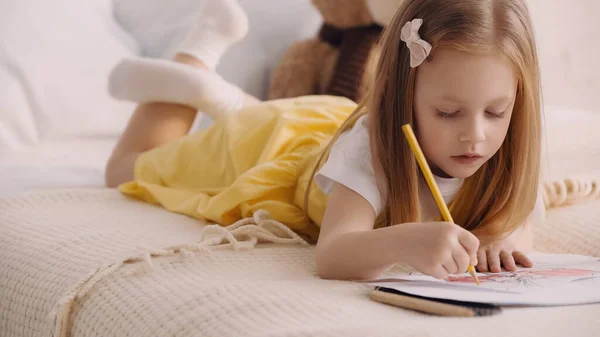 Child drawing on paper on blanket in bedroom — Stockfoto