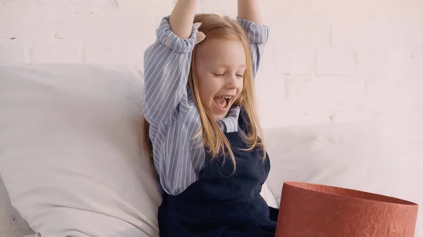 Excited kid looking at gift box on bed — Stock Photo
