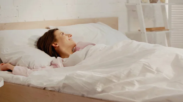 Positive brunette woman lying on bed at home — Stock Photo