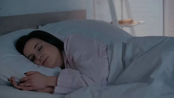 Brunette woman in pajamas sleeping on bed at home — Stock Photo