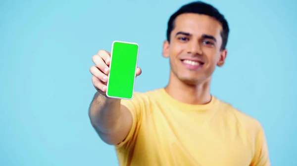 Blurred happy man holding smartphone with green screen isolated on blue — Stock Photo