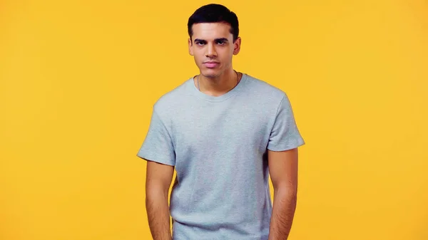 Displeased young man in t-shirt isolated on yellow — Stock Photo