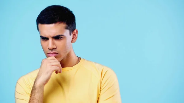 Пустотливий молодий чоловік в жовтій футболці мислення ізольовано на синьому — стокове фото
