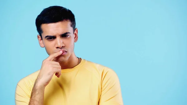 Pensive young man touching lips and thinking isolated on blue — Foto stock