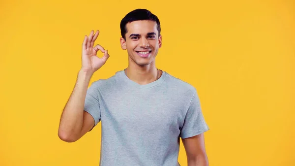 Щасливий молодий чоловік у футболці, що показує добре ізольований на жовтому — стокове фото