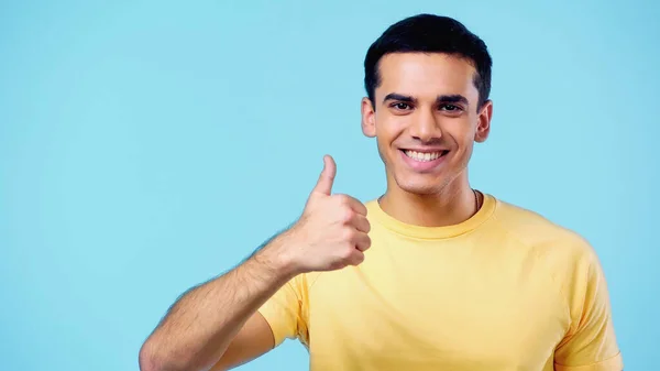 Позитивный молодой человек показывает большой палец на голубом фоне — стоковое фото