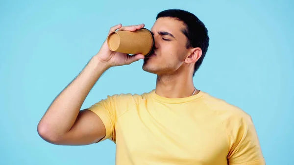 Jovem com olhos fechados bebendo café para ir isolado em azul — Fotografia de Stock