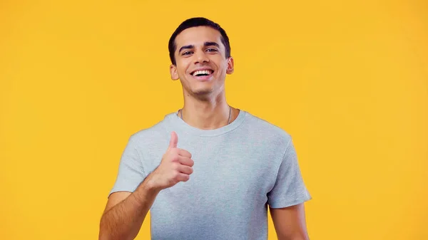 Sorridente homem em t-shirt mostrando polegar para cima isolado no amarelo — Fotografia de Stock