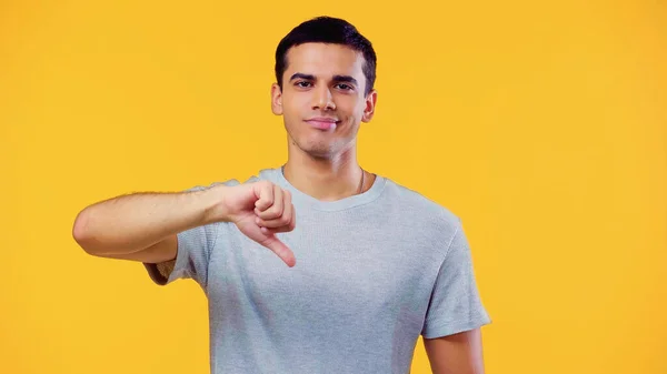 Dissatisfied young man in t-shirt showing dislike isolated on yellow — Stockfoto