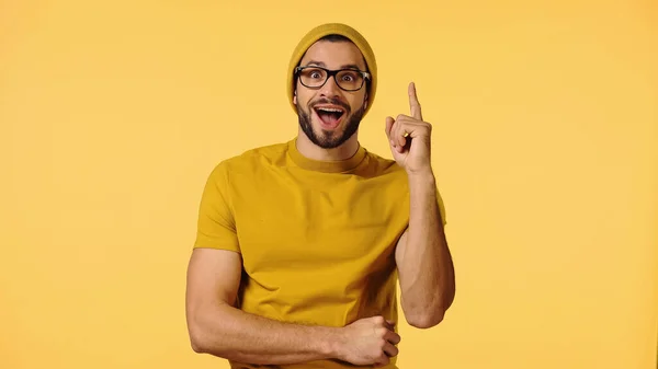 Verblüffter junger Mann mit Schirmmütze zeigt Ideenschild auf gelb — Stockfoto