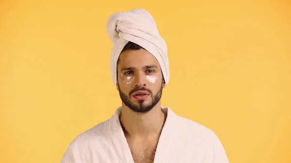 Homme dans les yeux patchs, peignoir et serviette isolé sur jaune — Photo de stock