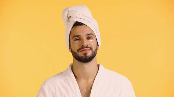 Pleased man in collagen eye patches isolated on yellow — Stock Photo