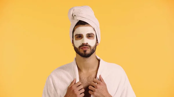 Hombre con máscara de arcilla en la cara mirando a la cámara aislada en amarillo - foto de stock