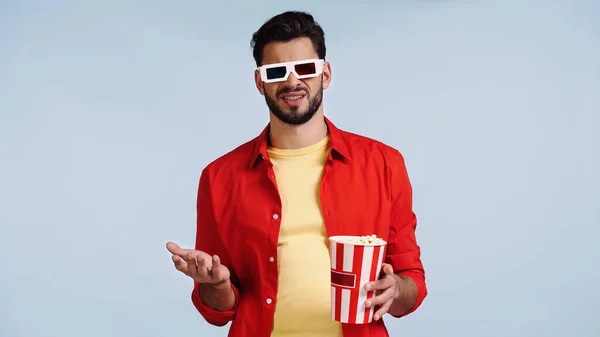 Unzufriedener Mann in 3D-Brille schaut Film und hält Popcorn-Eimer isoliert auf blauem Grund — Stockfoto