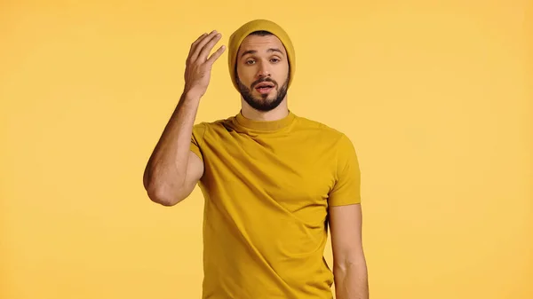 Scontento giovane in cappello beanie gesticolando isolato su giallo — Foto stock