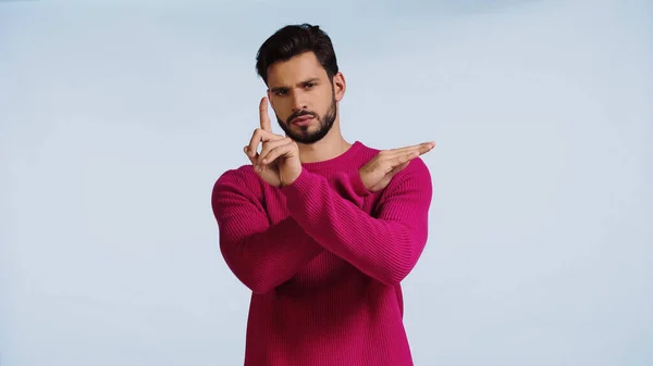 Hombre serio en suéter rosa cruzando las manos y señalando con el dedo aislado en azul - foto de stock