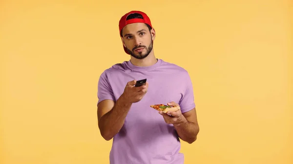 Homme barbu avec pizza regarder la télévision isolé sur jaune — Photo de stock