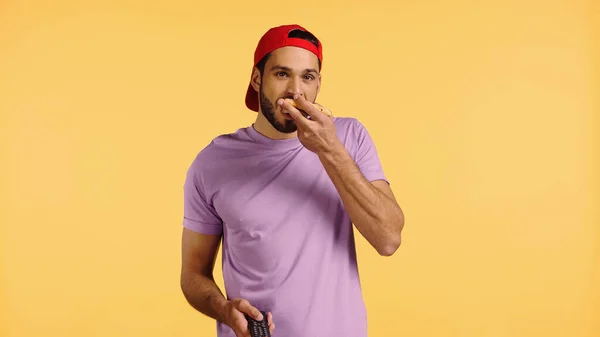 Jeune homme manger de la pizza et regarder la télévision isolé sur jaune — Photo de stock