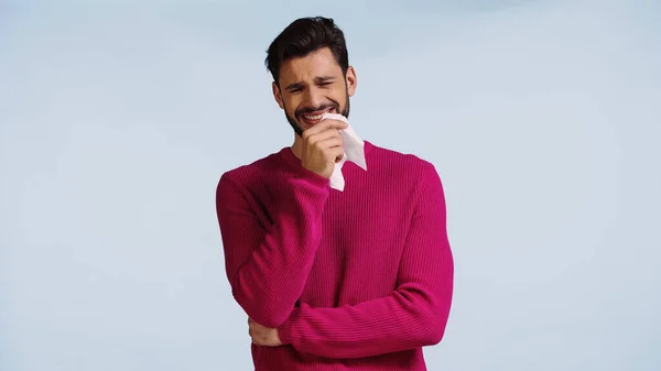 Frustrado hombre llorando y sosteniendo servilleta aislado en azul - foto de stock