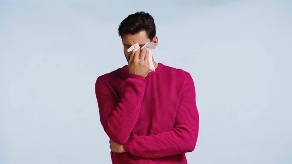 Hombre triste llorando y limpiando lágrimas con servilleta aislada en azul - foto de stock