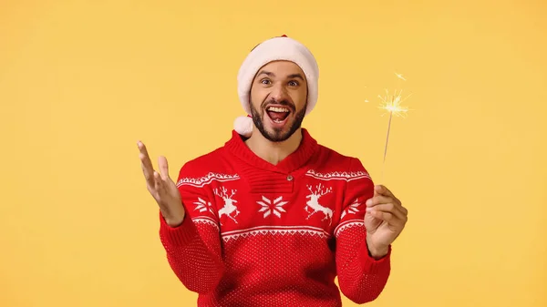 Amazed man holding shiny sparkler isolated on yellow — Stock Photo