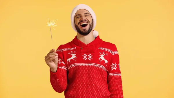 Positive man holding shiny sparkler isolated on yellow — Fotografia de Stock