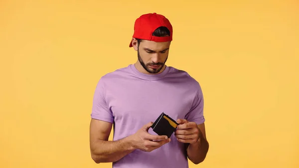 Upset man holding empty wallet isolated on yellow — Stock Photo