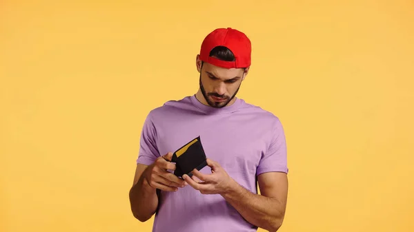 Triste hombre mirando la cartera vacía aislado en amarillo — Stock Photo