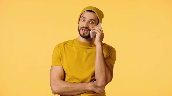 Sonriente hombre en gorro sombrero hablando en teléfono inteligente aislado en amarillo — Stock Photo