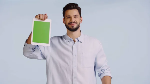 Happy man holding digital tablet with green screen isolated on blue — стоковое фото