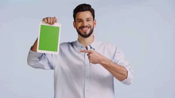 Homme heureux pointant du doigt à la tablette numérique avec écran vert isolé sur bleu — Photo de stock