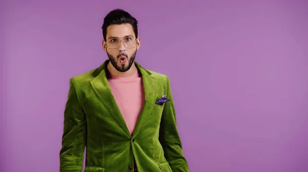 Shocked man in green jacket isolated on purple — Stockfoto