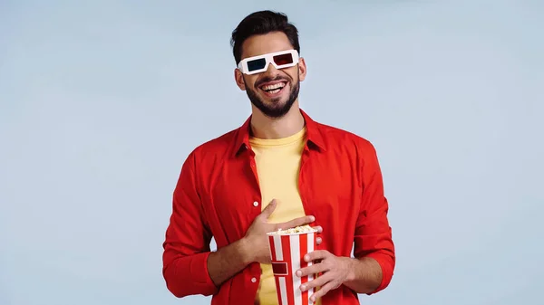 Glücklicher Mann in 3D-Brille schaut Film mit Popcorn isoliert auf blau — Stockfoto