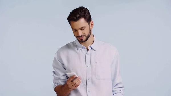 Hombre feliz utilizando el teléfono móvil aislado en azul - foto de stock