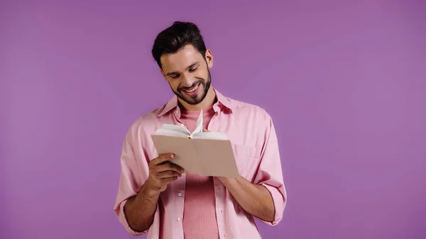 Felice uomo barbuto lettura libro isolato su viola — Foto stock