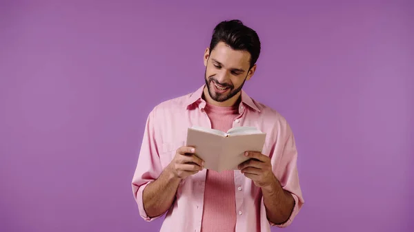 Hombre positivo y barbudo libro de lectura aislado en púrpura - foto de stock