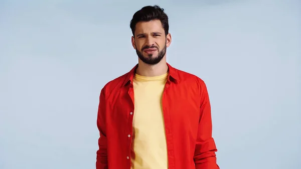 Displeased and bearded man in red shirt isolated on blue — Fotografia de Stock