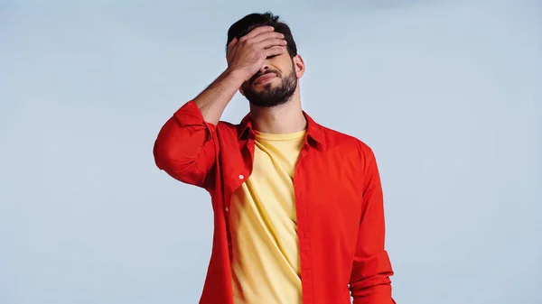 Uomo scontento e barbuto in camicia rossa facendo viso palmo isolato su blu — Foto stock