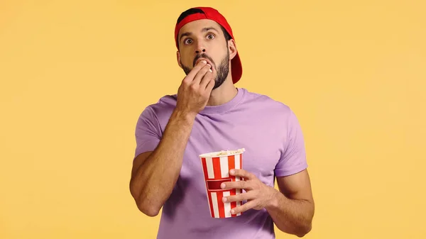 Человек смотрит кино и ест попкорн изолирован на желтый — стоковое фото