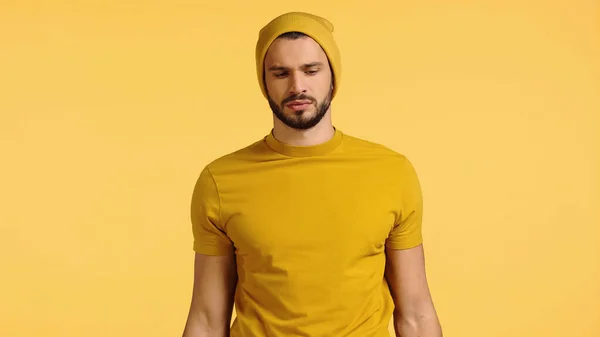 Upset young man in beanie hat isolated on yellow — Stock Photo