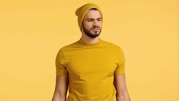 Displeased man in beanie hat smelling isolated on yellow — Stock Photo