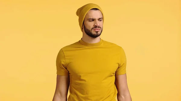 Displeased man in beanie hat smelling isolated on yellow — Stockfoto