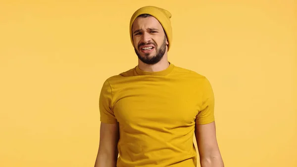 Upset man in beanie hat isolated on yellow — Stockfoto