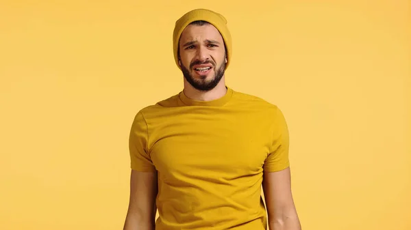 Dissatisfied man in beanie hat isolated on yellow — Stockfoto